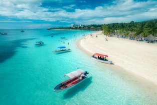 Łódki i turyści relaksujący się na plaży Zanzibaru