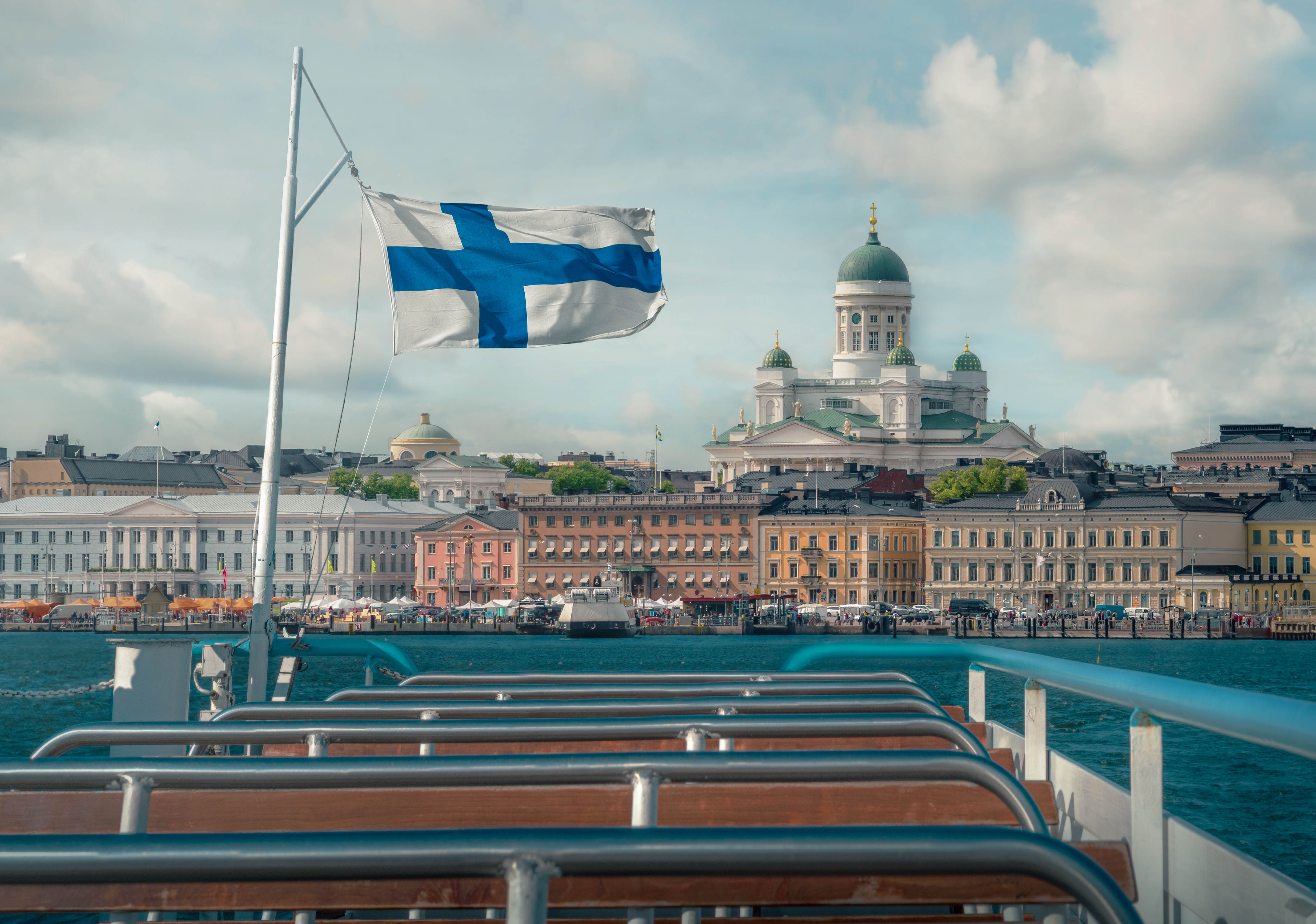 Flaga Finlandii na łódce, a w tle widok na stolicę - Helsinki