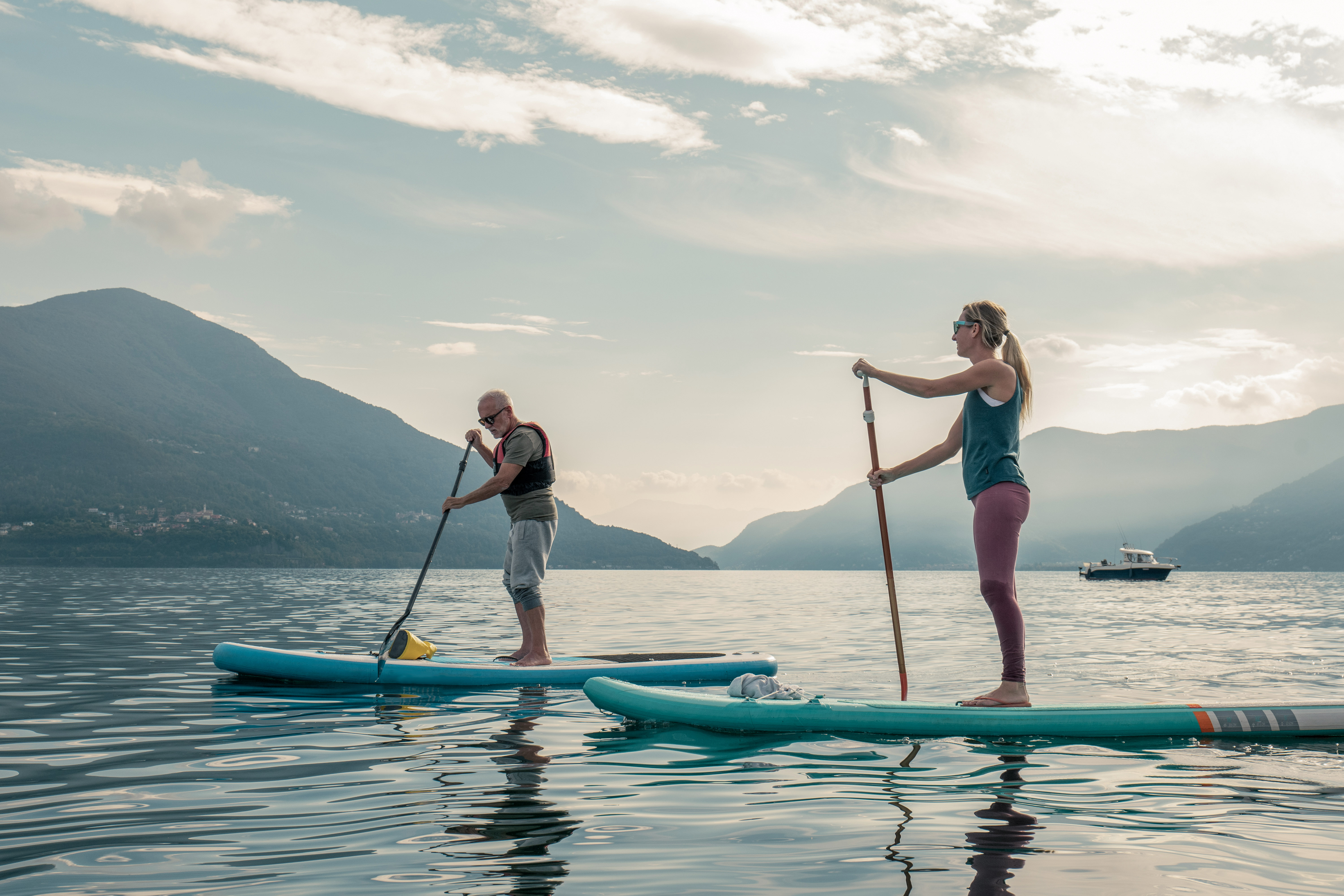 Dwoje ludzi płynących na deskach Stand Up Paddle po norweskim fiordzie