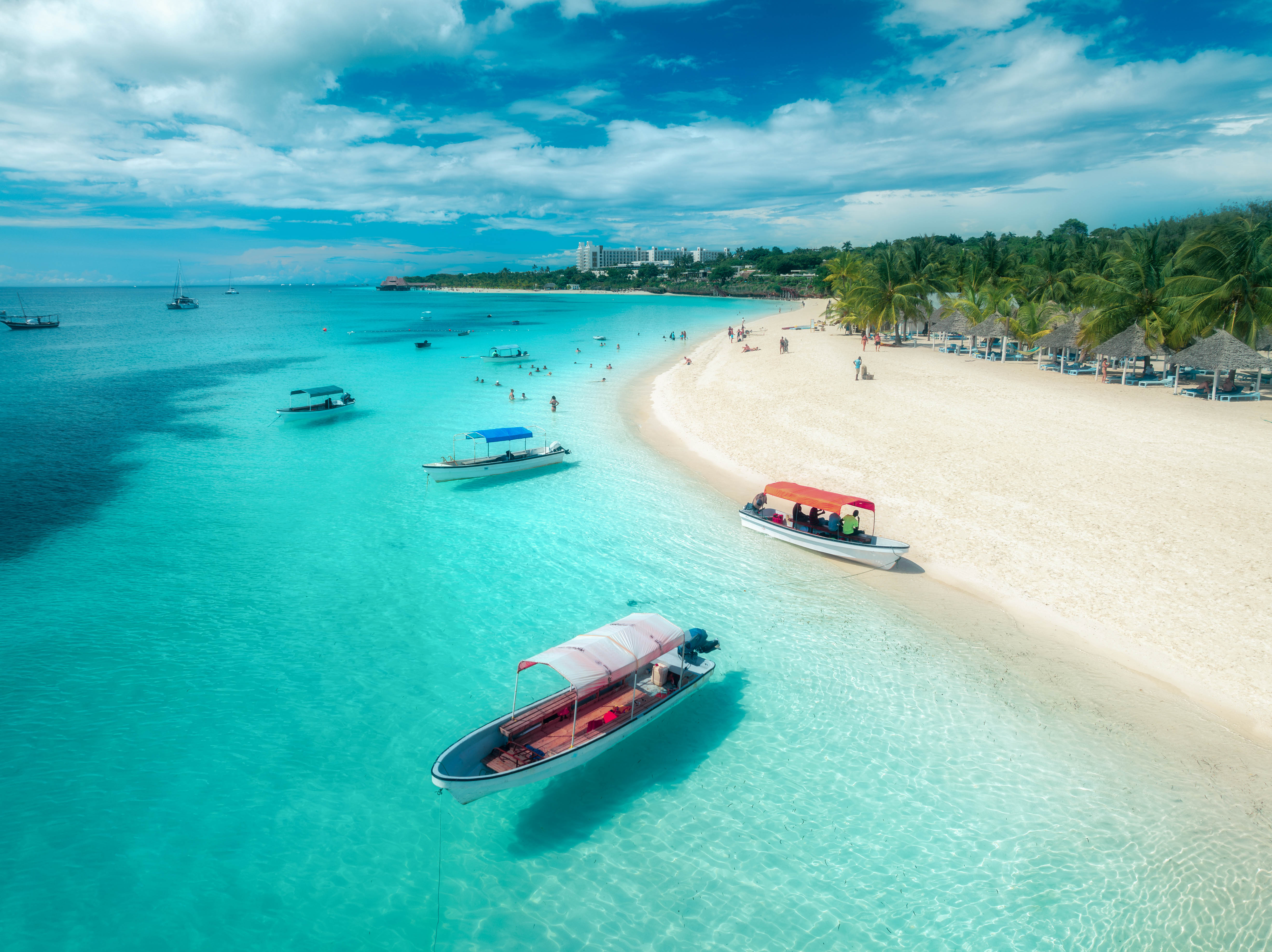 Łódki i turyści relaksujący się na plaży Zanzibaru